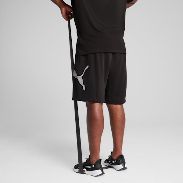A model against a grey backdrop exercises with a resistance band wearing black activewear.